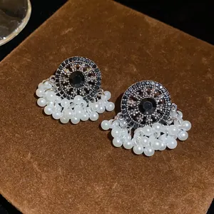Close-up of vintage ethnic earrings with black crystals and pearl tassels.
