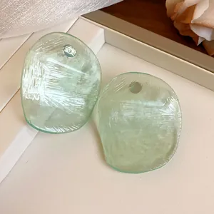 Macro view of light green translucent shrimp chip earrings with textured finish