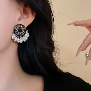 Close-up view of vintage ethnic style earrings with black stones and pearl tassels.