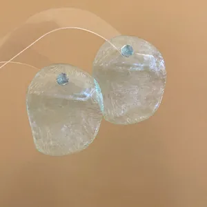 Detailed macro view of translucent textured shrimp chip earrings in pale yellow finish.