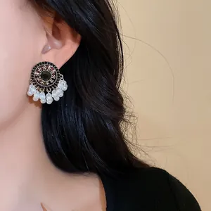 Detailed close-up of vintage ethnic earrings with pearls and black stone on a model.