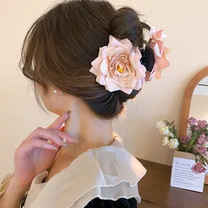 Close-up detail of a large pink rose fabric flower hair claw clip in a messy bun