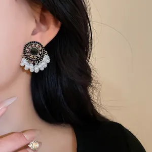 Close-up view of vintage ethnic tassel earrings with pearls and rhinestones on a model