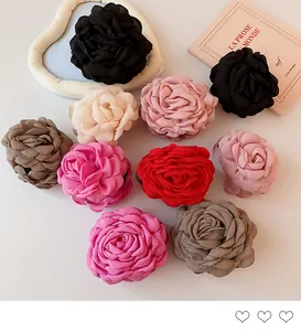Elegant fabric rose hair claw clips in various colors displayed with vintage book