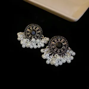 Close-up view of retro ethnic stud earrings featuring black stones and pearl tassels.