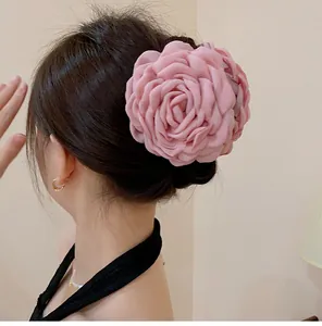 Close-up of a large pink fabric rose hair claw clip worn on a bun hairstyle for women