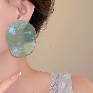 Macro view of translucent green irregular earring with ripple texture on model