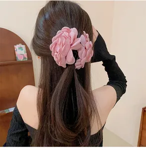 Close-up of elegant pink fabric rose flower hair claw clip on long wavy hair.