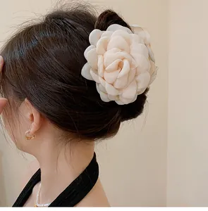 Close-up back view of a large cream chiffon rose flower hair claw clip on dark styled hair