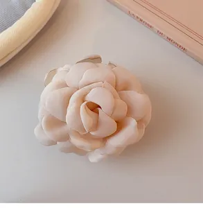 Detail view of a soft pink fabric rose hair claw clip with layered petals