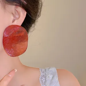 Close-up of large red translucent round earrings with unique shrimp chip texture.