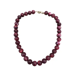 Élégant collier de perles bordeaux marbré avec un fermoir mousqueton doré sur fond blanc