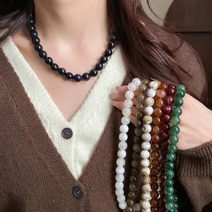 Vue rapprochée détaillée de plusieurs colliers de perles colorés avec un cardigan vintage