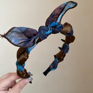 Close-up detail of a braided bow headband wrapped in elegant brown and blue floral fabric