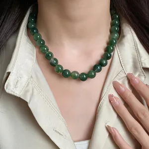 Détail d'un élégant collier de perles vertes porté par un mannequin sur une chemise