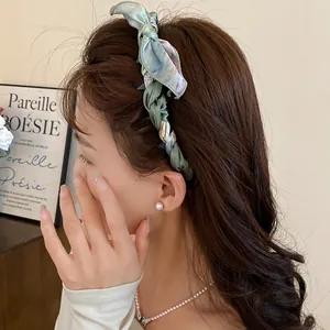 Close-up detail of a vintage floral silk scarf wrapped headband with bow on model's hair