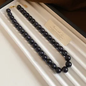 Gros plan détaillé d'un collier de perles marbrées sombres sur un plateau d'exposition