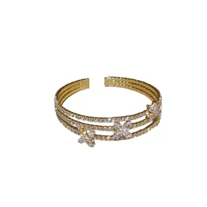 Bracciale rigido dorato di lusso con tre file e ciondoli a farfalla in zircone scintillanti.