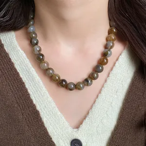 Gros plan détaillé d'un collier de perles marbrées sur mannequin au style rétro élégant