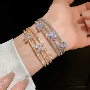 Dettaglio di bracciali rigidi in oro e argento con scintillanti fiori di zircone