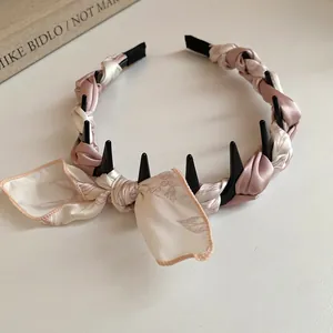 Detailed view of pink silk scarf wrapped headband featuring an elegant bow design