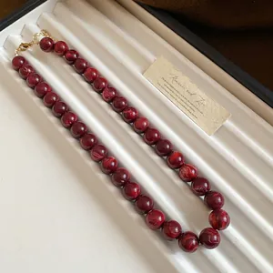 Détail d'un collier de perles rouges marbrées élégantes avec un fermoir doré rétro