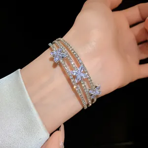 Primo piano dettagliato di un bracciale rigido a tre fili con fiori di strass.