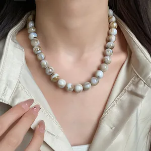 Vue rapprochée d'un collier de perles marbrées porté avec un élégant chemisier en satin