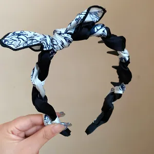 Detail view of a braided silk scarf headband with a black and white floral bow.