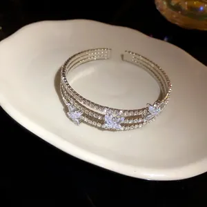 Primo piano di un bracciale rigido argento con farfalle scintillanti in zirconi