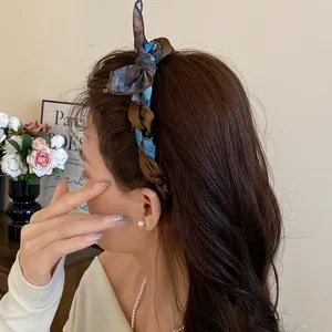 A detailed side view showing an elegant silk scarf wrapped bow headband on a model