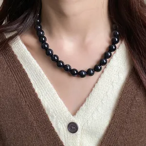 Vue détaillée d'un collier ras du cou élégant à perles noires porté par un mannequin
