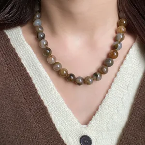 Gros plan d'un collier de perles marbrées élégant sur un mannequin en cardigan d'automne
