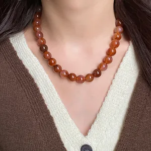 Collier ras-du-cou élégant avec des perles marbrées rouge-brun en gros plan sur un modèle