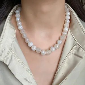 Détail du collier de perles à motif lavis d'encre porté avec une chemise en soie champagne