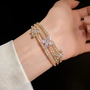 Dettaglio di un elegante bracciale rigido dorato a tre strati con fiori in zircone