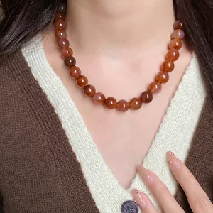 Détail exquis d'un collier ras du cou rétro en perles marbrées marron-rouge sur modèle
