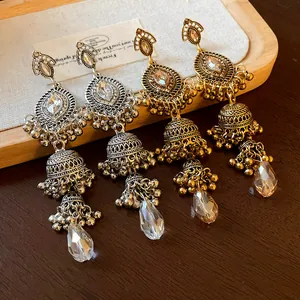 Close-up view of vintage palace style gold and silver jhumka earrings with crystals