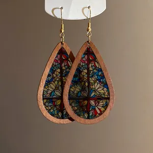 Close-up of teardrop wooden earrings with colorful stained glass mosaic pattern.