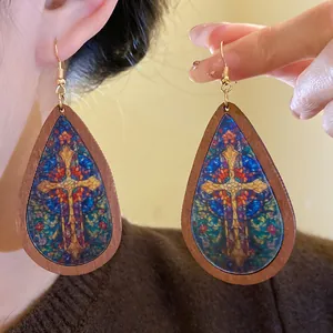 Close-up detail of vintage bohemian teardrop wooden earrings with stained glass cross print