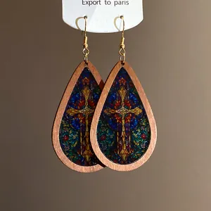 Close-up view of bohemian teardrop wood earrings with intricate stained-glass cross print