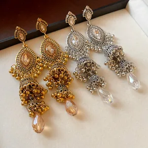 Detail of vintage palace style Jhumka dangle earrings with crystals in gold and silver.