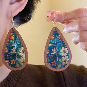Detail view of bohemian wooden teardrop earrings with stained glass floral print