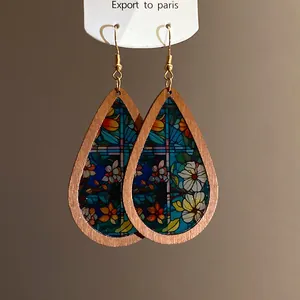 Detailed macro view of bohemian wooden teardrop earrings featuring colorful floral print
