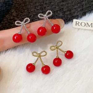 Detailed view of elegant red cherry earrings with bow design on soft white fur