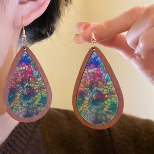 Macro detail of Bohemian teardrop wooden earrings with vibrant colorful mosaic print