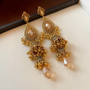 Detailed macro view of vintage gold jhumka earrings featuring champagne faceted crystal drops