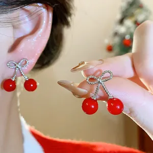 Close-up detail of silver-tone bow-knot cherry earrings with red glossy beads