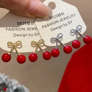 Detail of red cherry bowknot earrings with gold and silver metal finishes on S925 silver card.