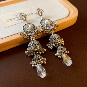 Macro shot of vintage silver-toned palace style earrings with clear teardrop crystal pendants.